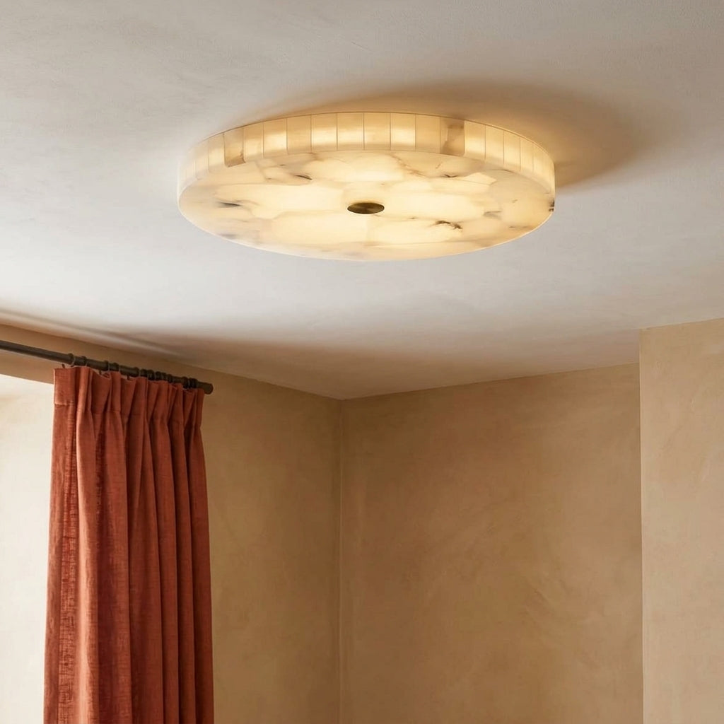 A round flush-mount ceiling light fixture with a warm white and cream marbled pattern, installed on a textured off-white ceiling in a room with beige walls and rust-colored curtains.
