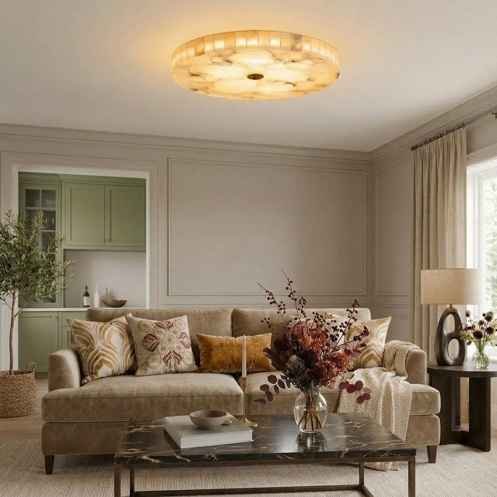 A round flush-mount marble ceiling light glowing in a styled living room with a beige sofa and floral arrangements.