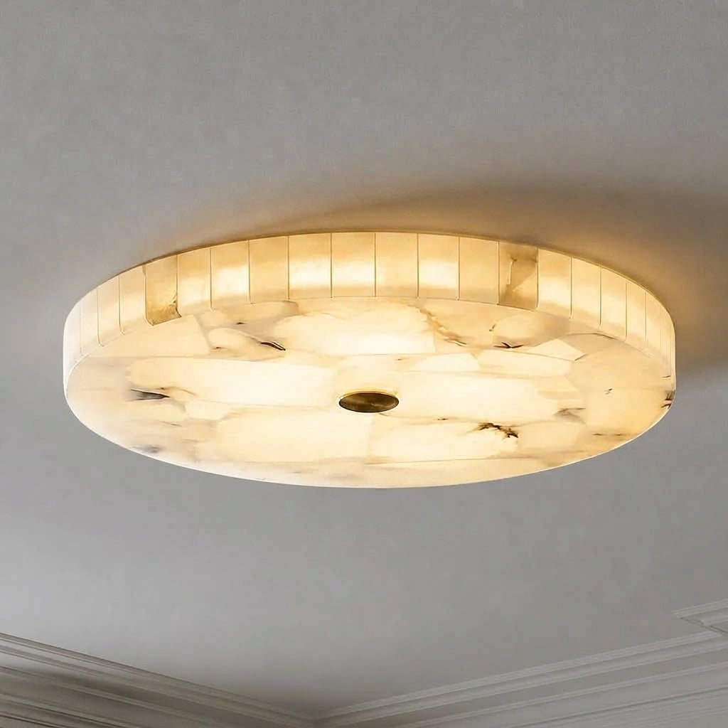A round marble flush-mount ceiling light fixture glowing with a soft warm light against a neutral grey ceiling.