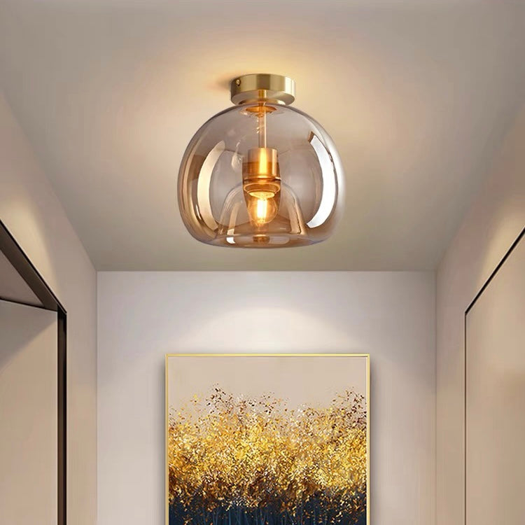 Amber glass globe compact pawo ceiling light casting a warm glow above hallway artwork