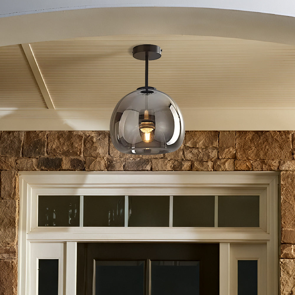 Compact smoke grey glass globe pawo ceiling light installed on a covered rustic brick porch