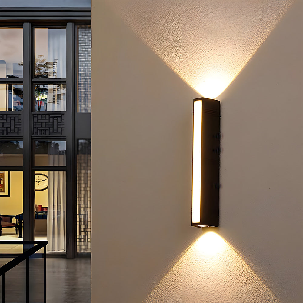 Modern peqi black tube wall light installed on an architectural pillar casting a warm up and down glow