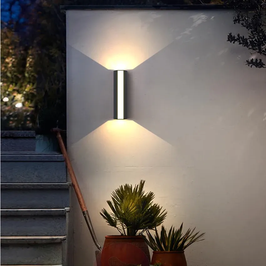 Modern outdoor peqi LED sconce illuminating a garden staircase and potted plants at night