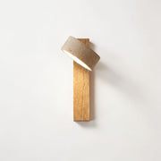 Pexni wabi sabi wall light with rotatable travertine stone shade on log wood backplate, mounted on a white wall