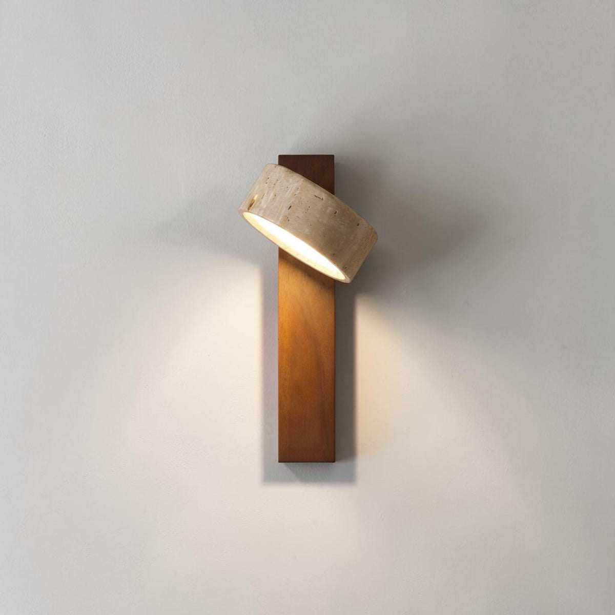 Pexni wall light illuminated, walnut wood backplate with warm glow from the stone shade, studio grey background