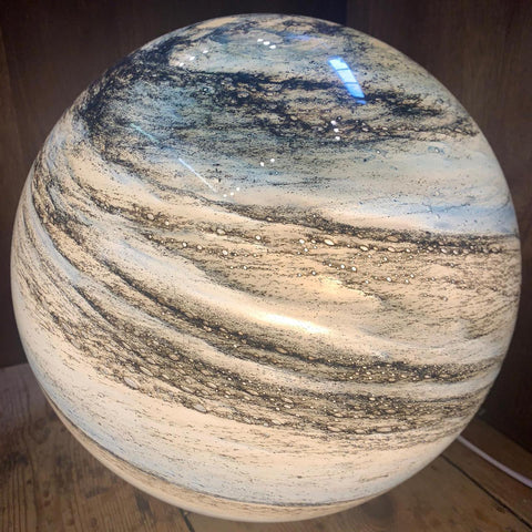 Close-up detail of the pilo glowing beige and brown planetary glass sphere, highlighting its intricate swirling surface pattern