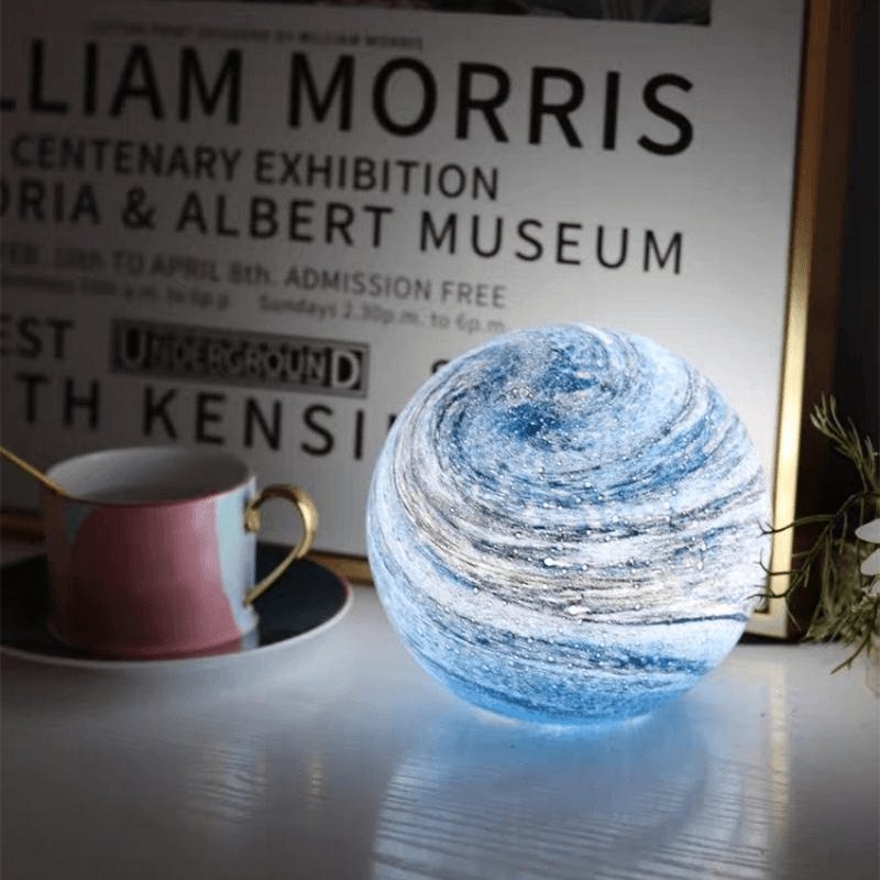 Blue pilo marbled glass sphere acting as a beautiful desk decor accent next to a framed poster and coffee mug