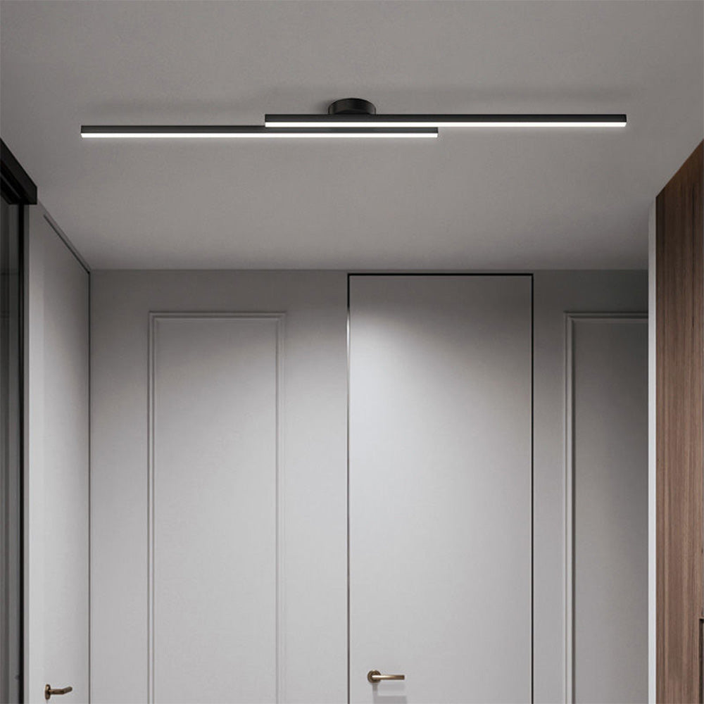 Black minimalist linear poxu ceiling light illuminating a bright, modern white hallway