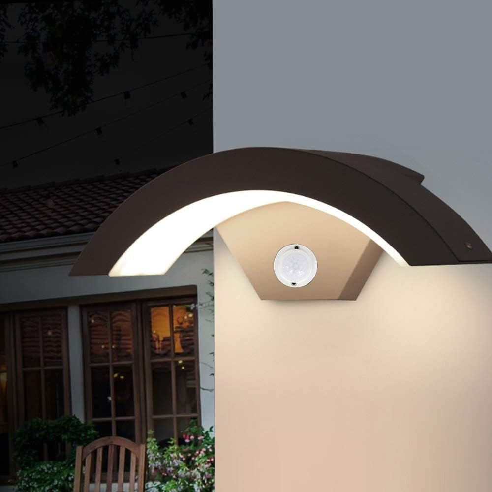Close-up of the qaxo arched motion sensor porch light glowing warmly on an exterior wall at dusk