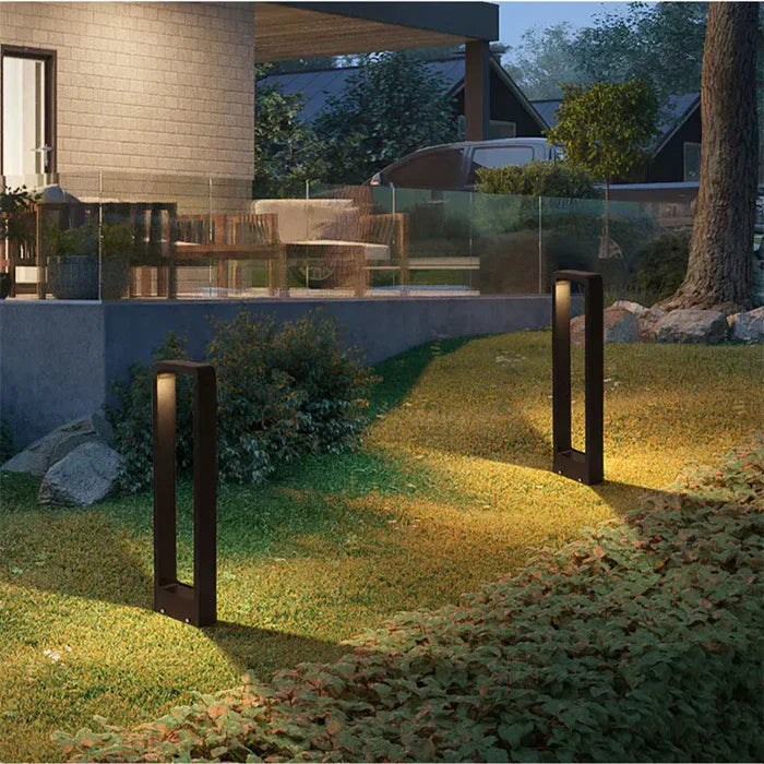 qura black architectural LED path lights lighting up a grassy slope near a modern outdoor patio