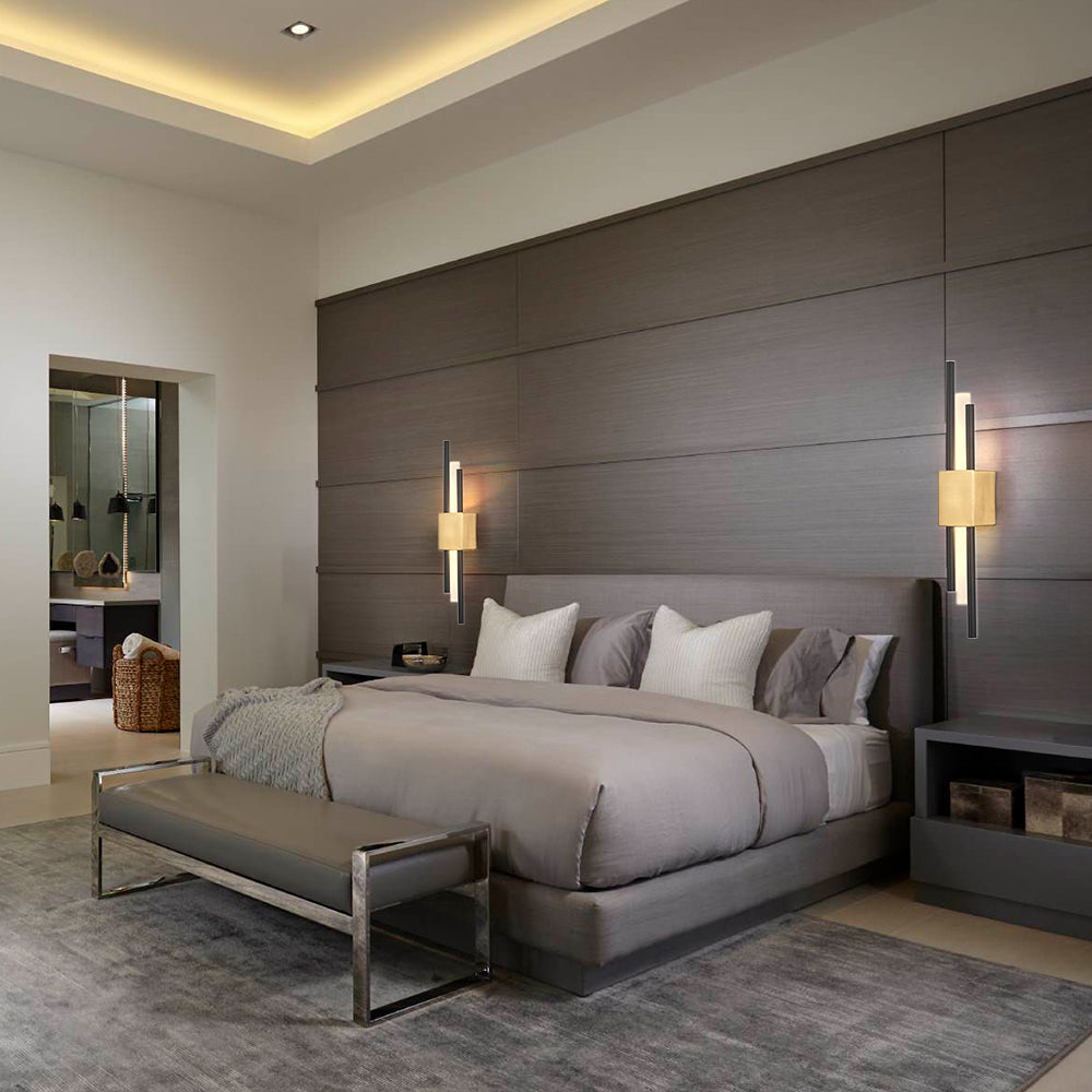 Two-tone gold and black qytu staggered LED sconce providing a warm, cosy glow in a modern bedroom