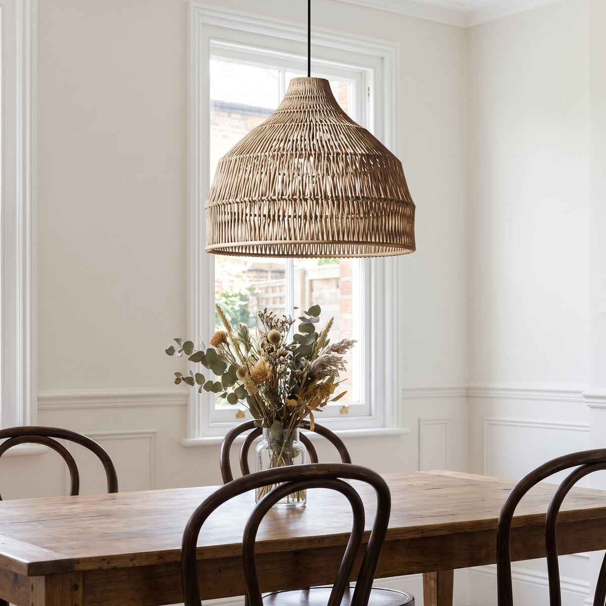 Relton rattan pendant light above a wooden dining table with bentwood chairs in a British dining room