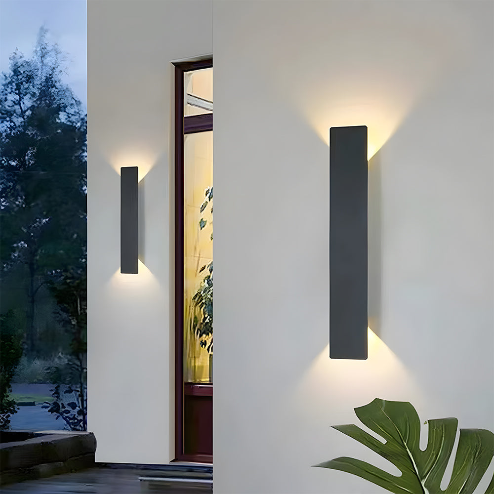 reta modern slim black LED outdoor wall light casting up and down illumination on a white exterior wall