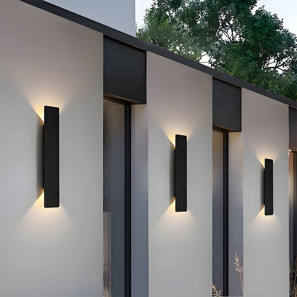 Three slim architectural exterior reta wall lights installed on a contemporary white facade
