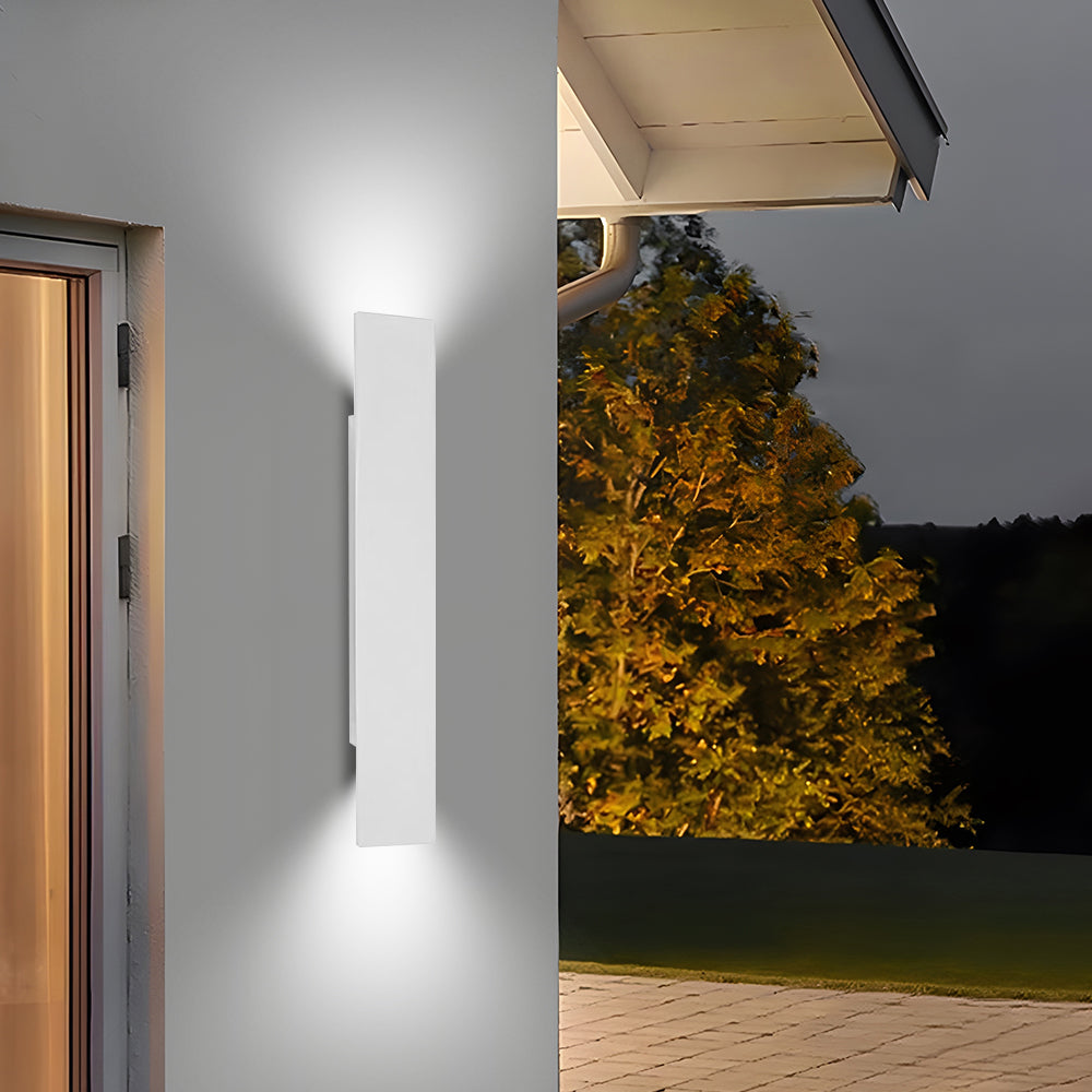 White exterior up and down reta wall sconce glowing warmly against a light wall
