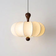 Rizqo wabi sabi fabric pendant light with walnut wood cap, illuminated on a white wall