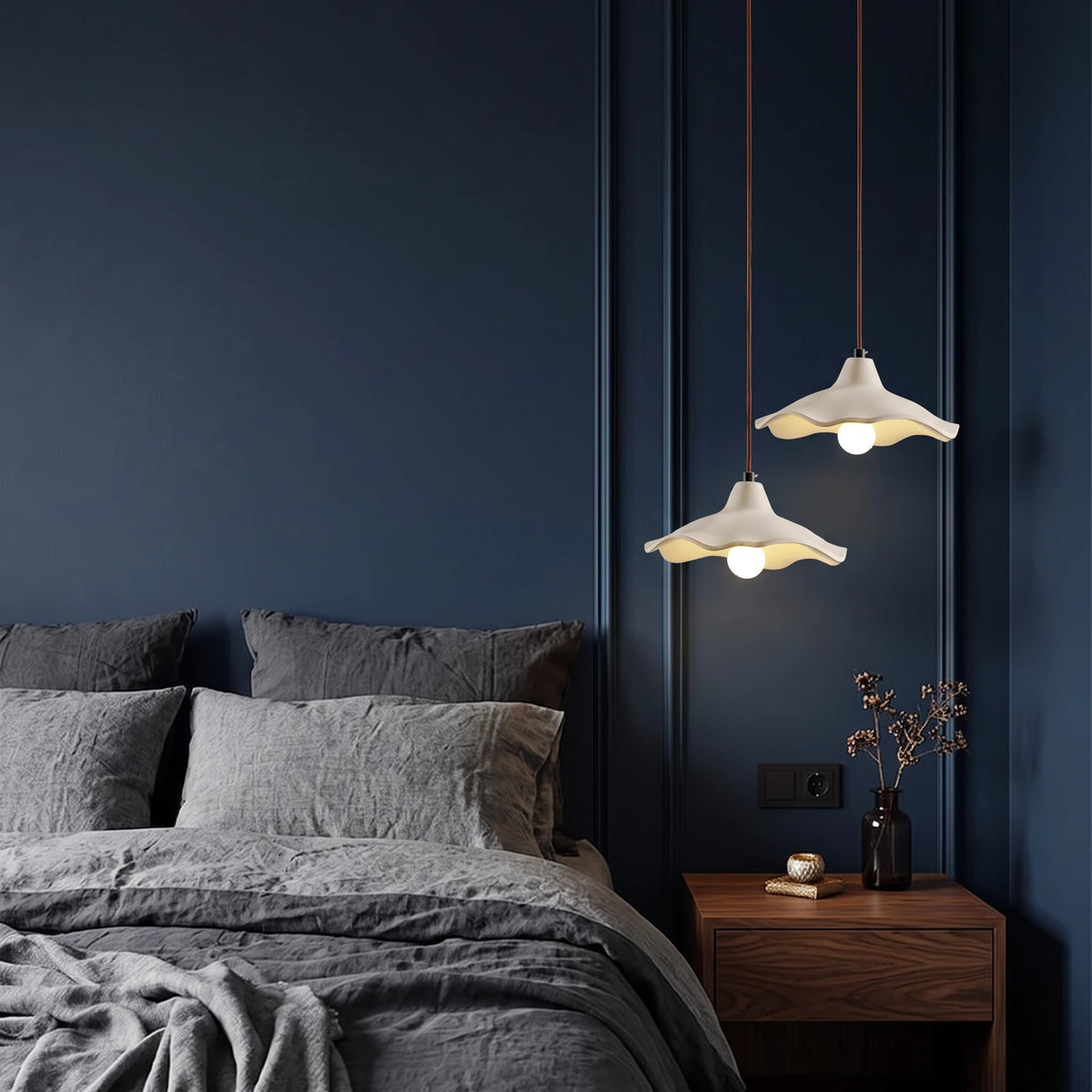 2 Rylin scalloped concrete bell pendant lights hanging beside a bed as bedside lighting in a deep navy bedroom