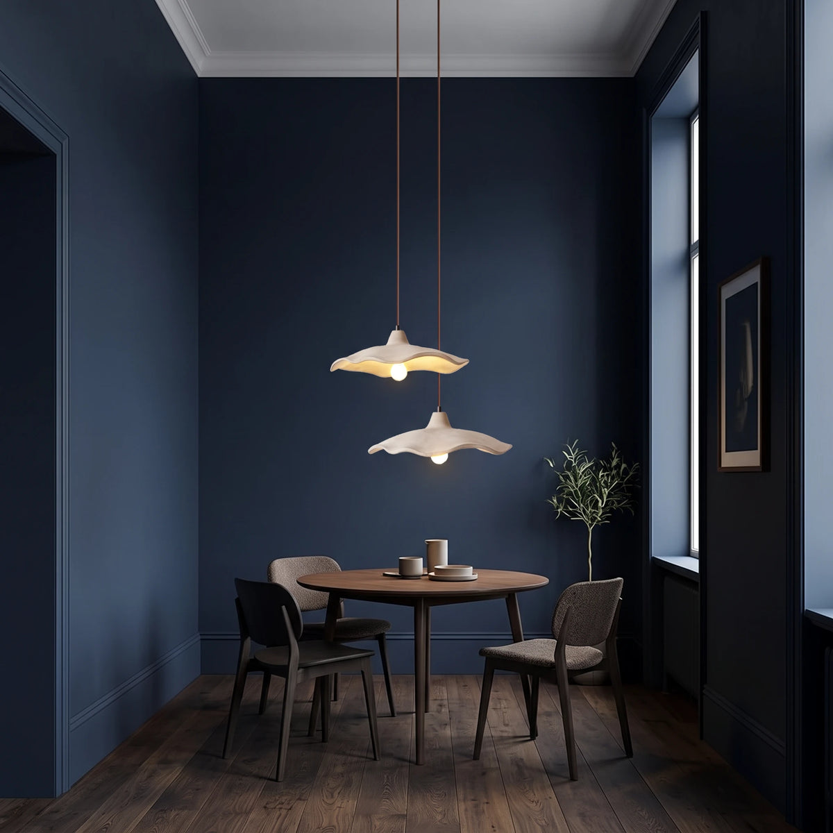 2 Rylin scalloped concrete bell pendant lights hanging above a small round dark oak table in a deep navy dining nook