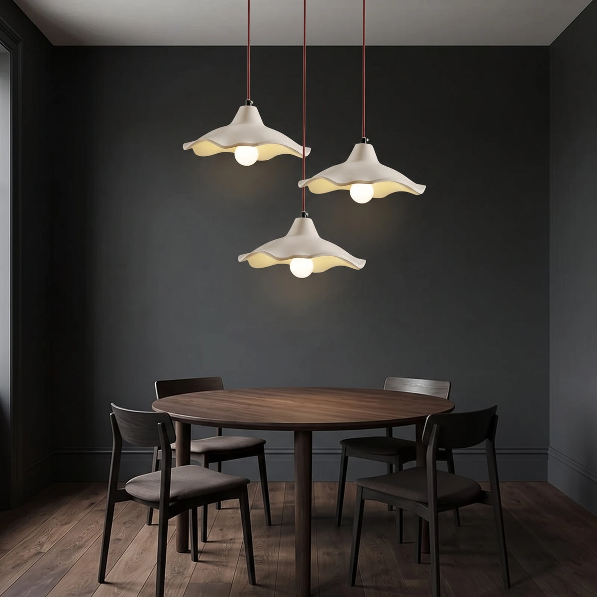 3 Rylin scalloped concrete bell pendant lights hanging at different heights above a round dark oak dining table in a charcoal room