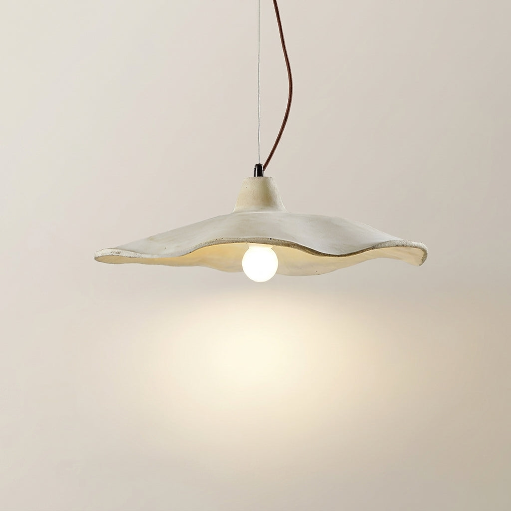 Close-up of the Rylin scalloped concrete bell pendant light switched on with a warm glow from the bulb
