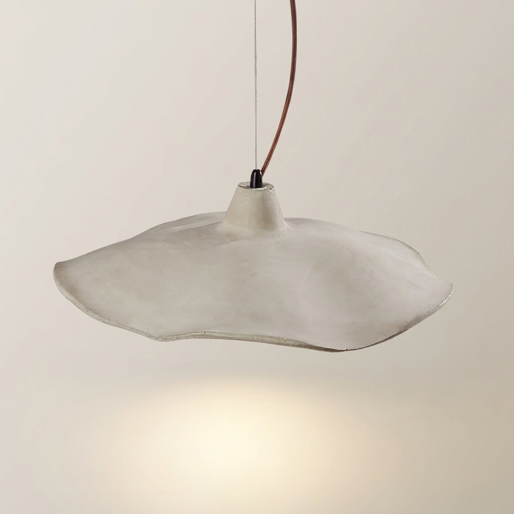 Close-up of the Rylin scalloped concrete bell pendant light with its wavy rim and black cord connector
