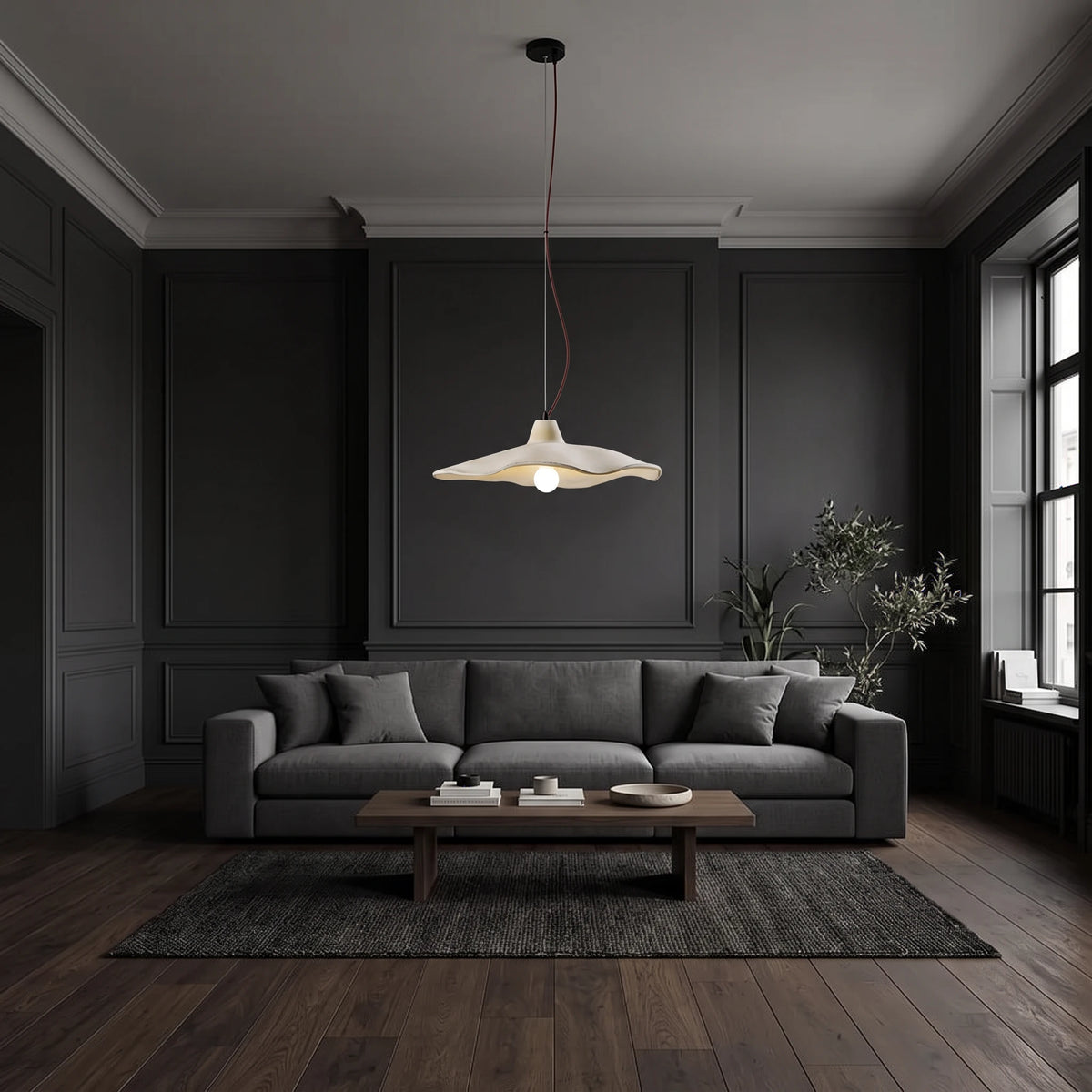 Rylin scalloped concrete bell pendant light hanging above a coffee table in front of a dark grey sofa in a charcoal living room