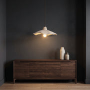 Rylin scalloped concrete bell pendant light hanging above a dark oak sideboard against a charcoal wall