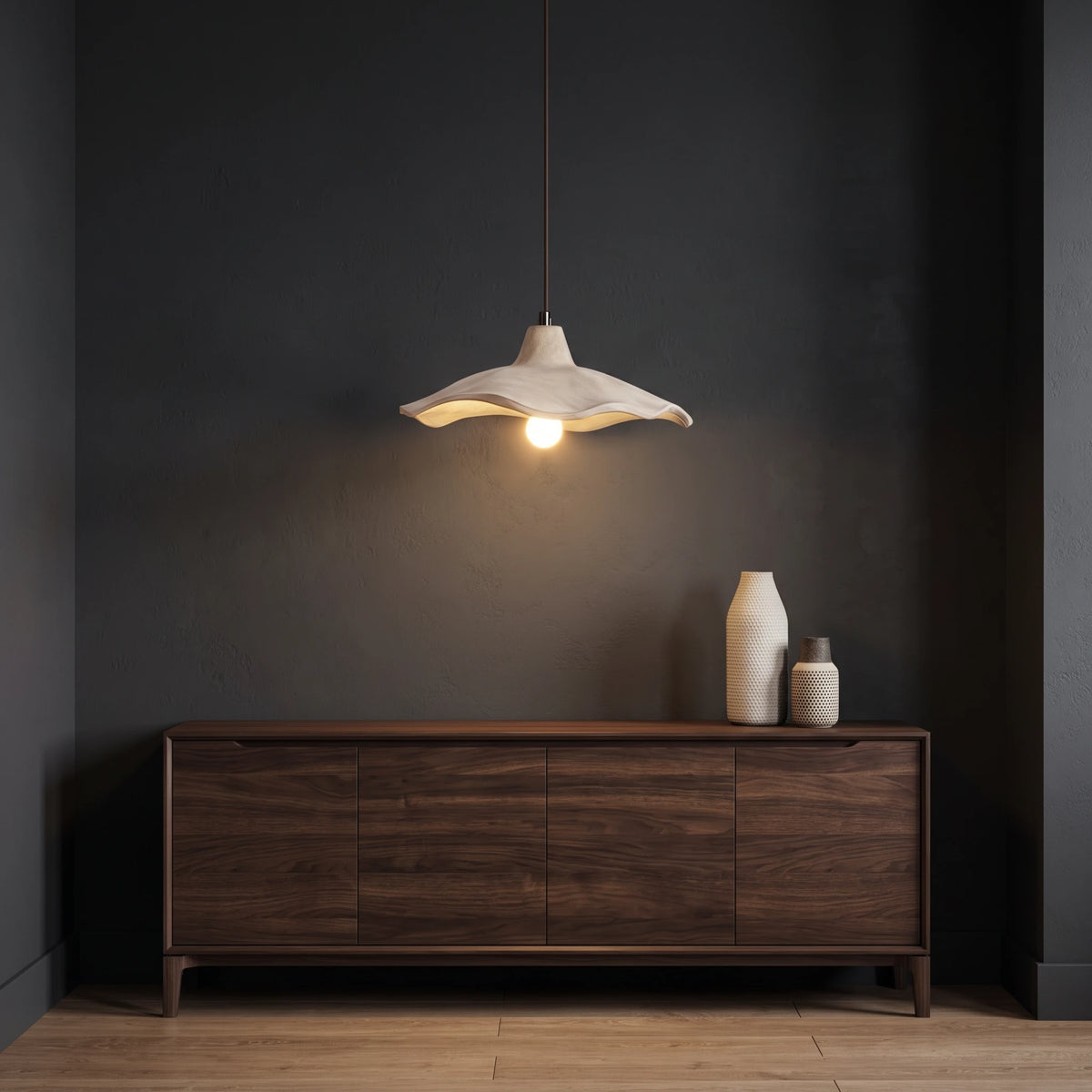 Rylin scalloped concrete bell pendant light hanging above a dark oak sideboard against a charcoal wall