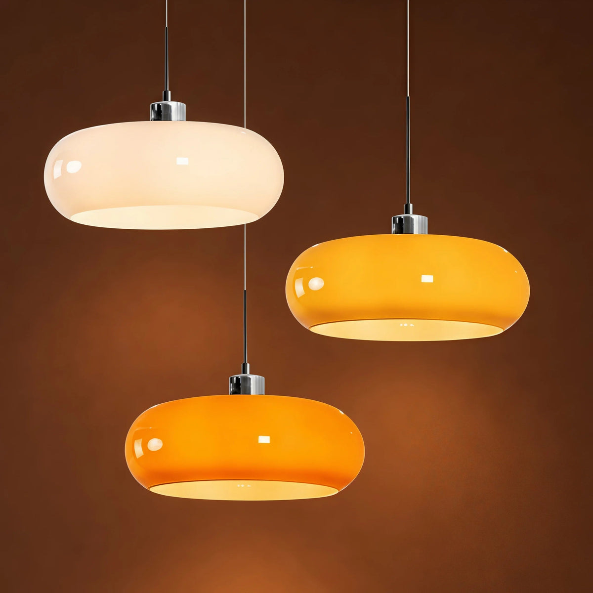 Cluster of three retro glass seqa dome pendant lights in white, brown, and orange illuminating a dark setting