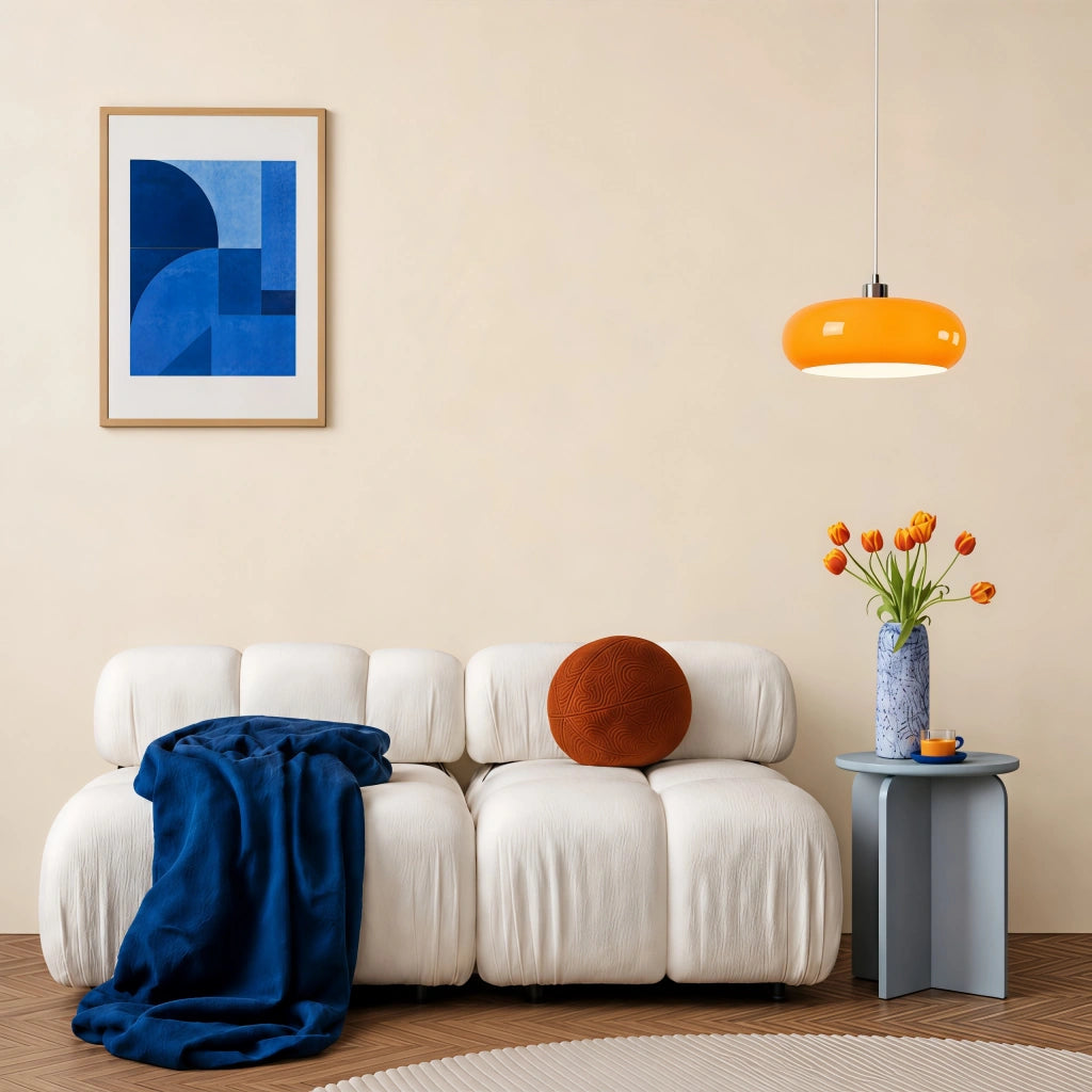Orange Nordic seqa glass pendant acting as a vibrant accent light over a white ribbed living room sofa