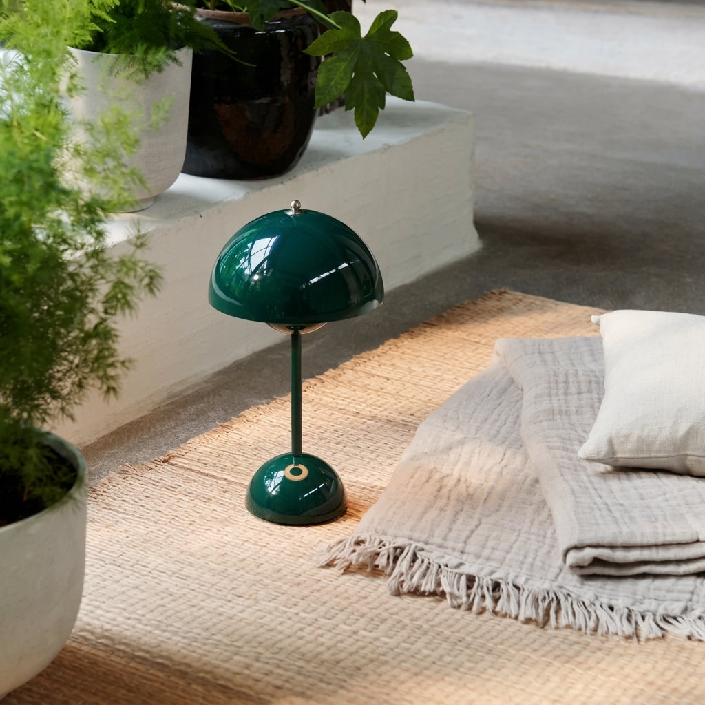 Green sulba table lamp on a floor with plants and a blanket in the background