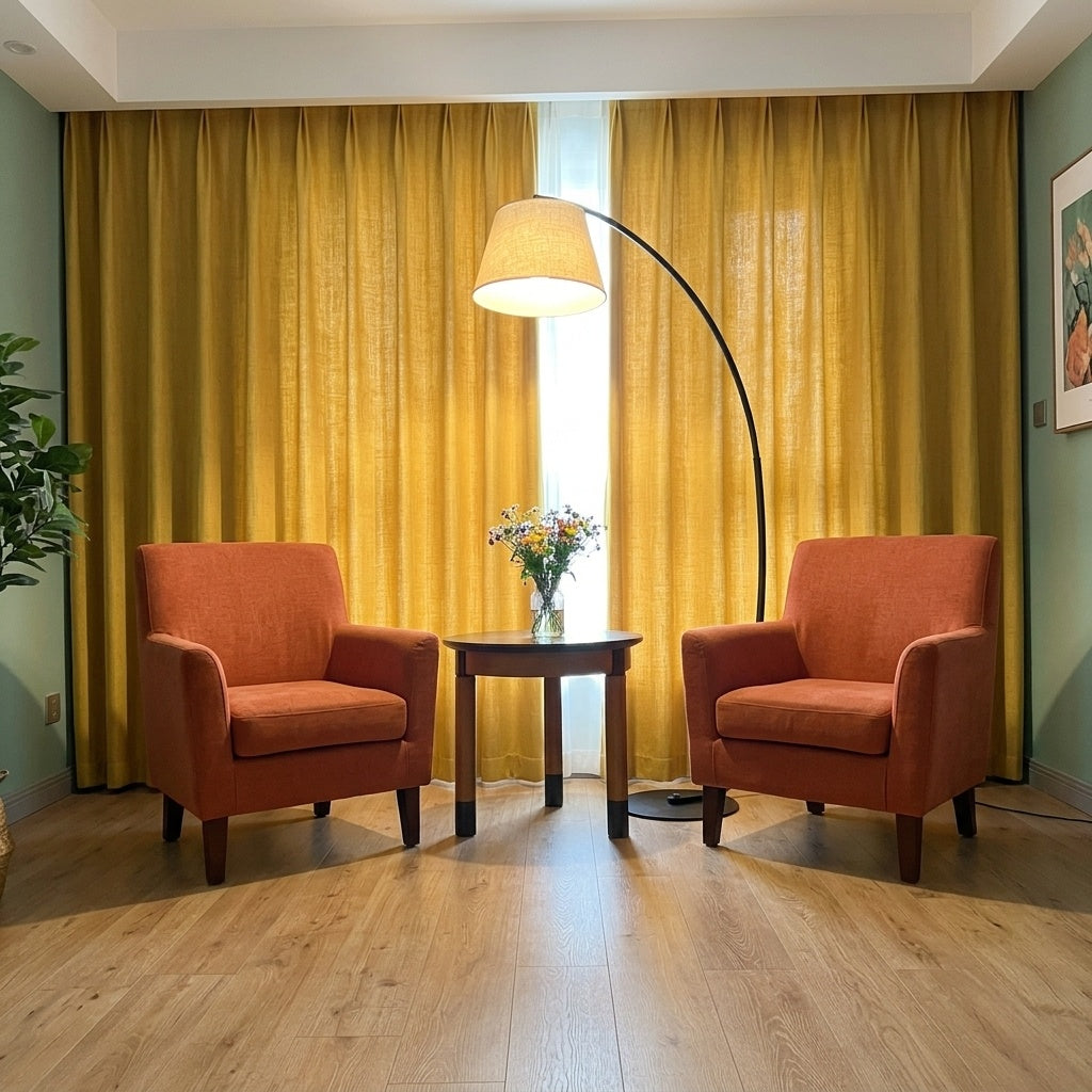 Tavio arc floor lamp arching over a round side table between 2 terracotta armchairs in a sage green living room