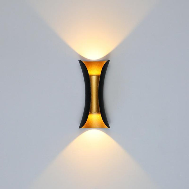 Architectural black and gold teka exterior wall sconce casting warm up and down illumination