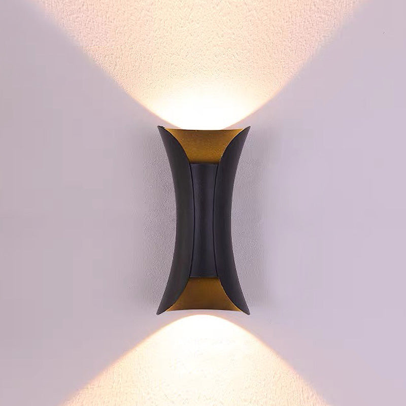 Minimalist black teka hourglass LED outdoor wall light providing an even wall washing glow