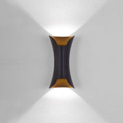 Modern black and gold teka hourglass LED outdoor wall light casting a sharp V-shaped beam