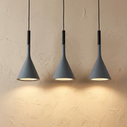 Three graphite Nordic funnel ters pendant lights illuminating a textured beige wall with a warm, focused glow