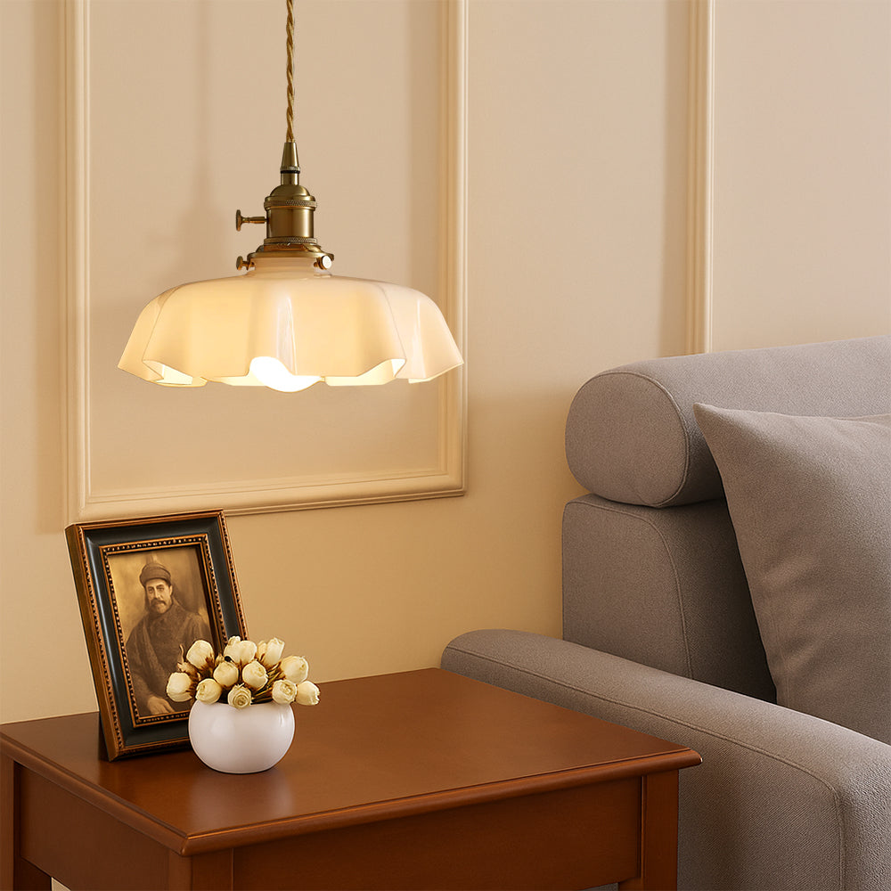 Antique brass scalloped tugyl pendant light illuminating a wooden side table next to a grey lounge sofa