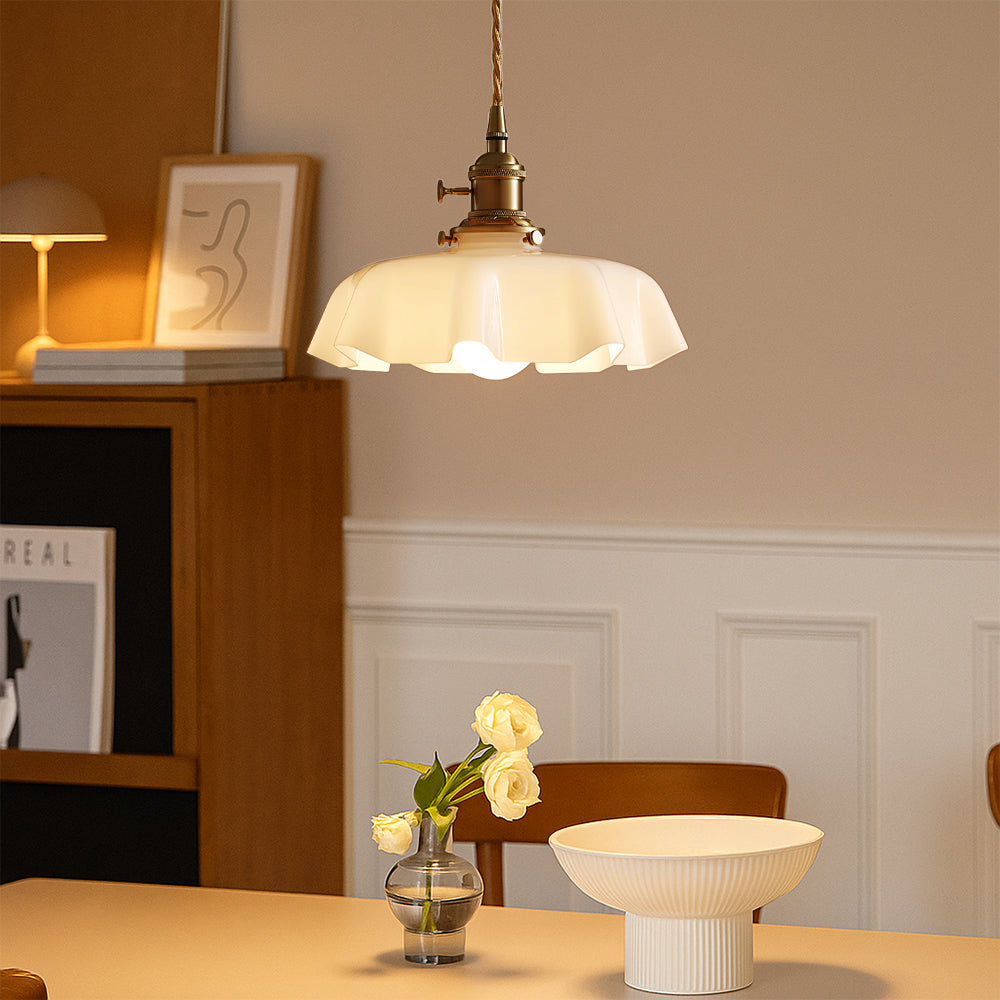 Retro brass and cream tugyl glass chandelier suspended over a minimalist dining table providing a warm ambient glow