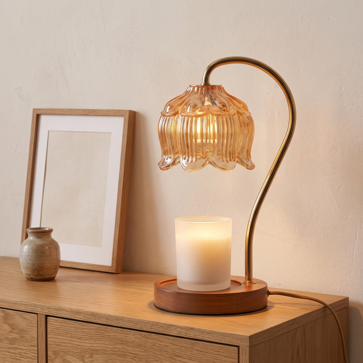 Tulvi amber glass tulip candle warmer lamp lit on a wooden surface