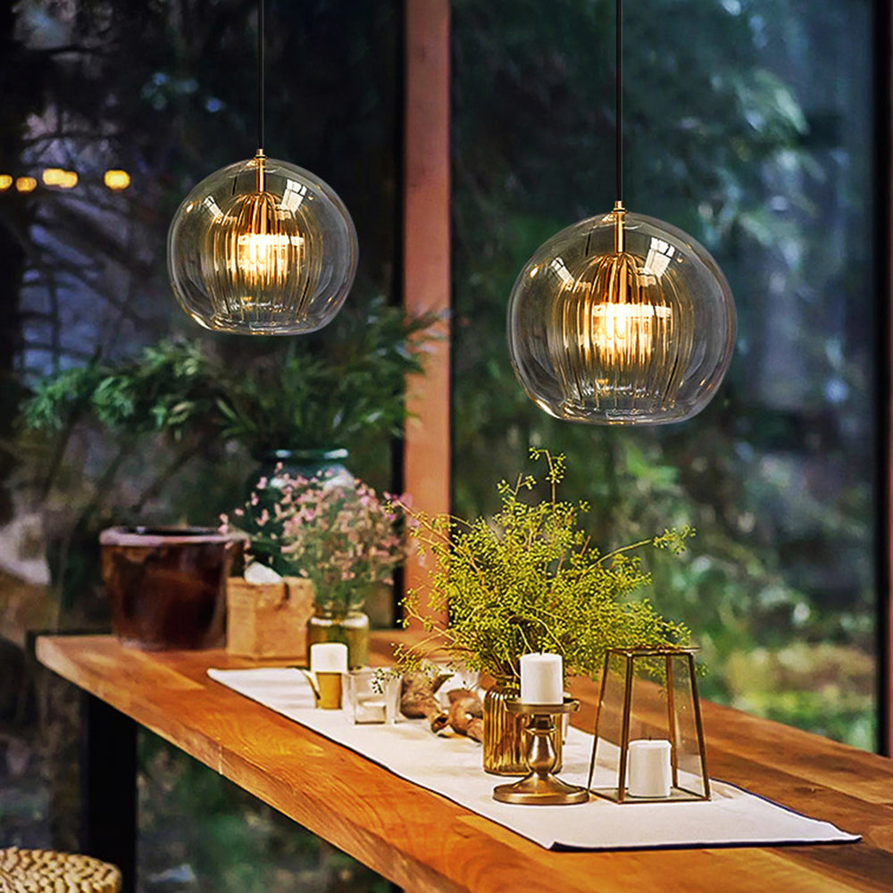 Pair of amber double-layer glass globe tuoj pendants illuminating a rustic wooden dining table