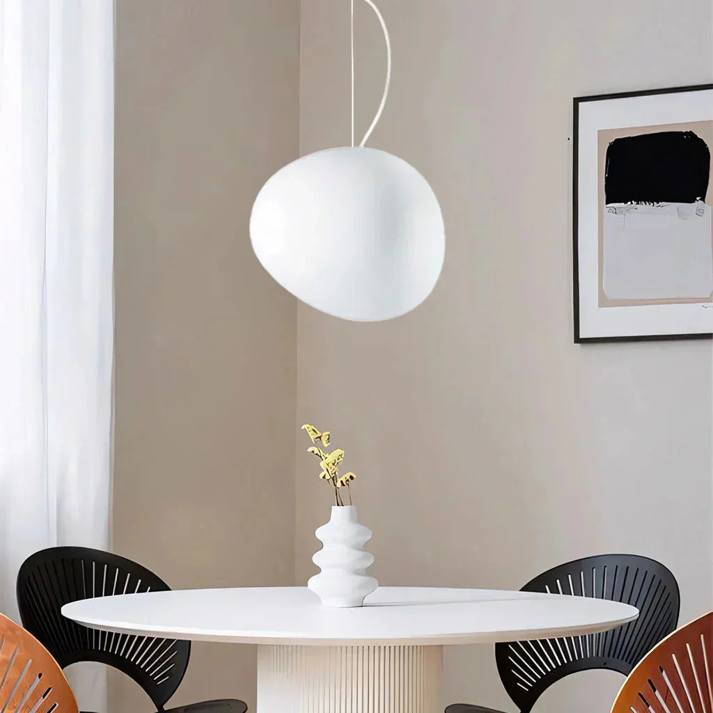 Single frosted glass tupel pendant light suspended over a round dining table in a bright room