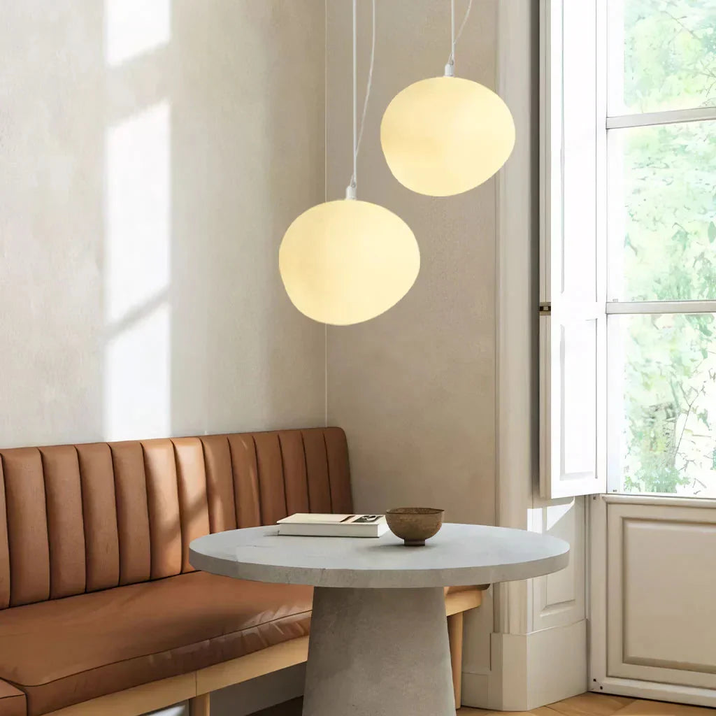Pair of organic glass pebble tupel pendants providing warm ambient lighting over a dining banquette