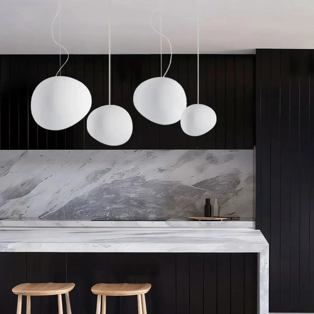 Three white glass tupel pendant lights illuminating a sleek modern kitchen island