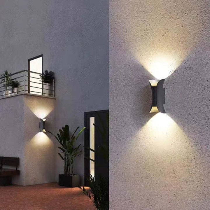 Pair of teka modern hourglass outdoor wall lights illuminating a contemporary home facade in the evening