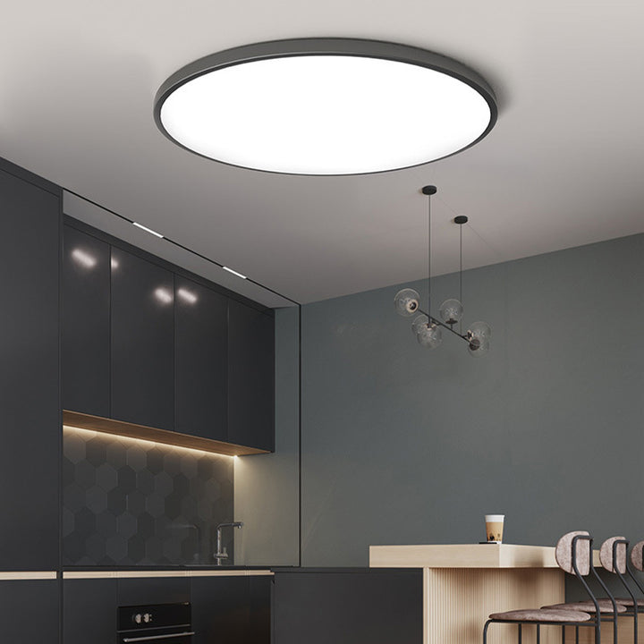 Modern black round LED tywa ceiling lamp providing sleek overhead lighting in a dark modern kitchen