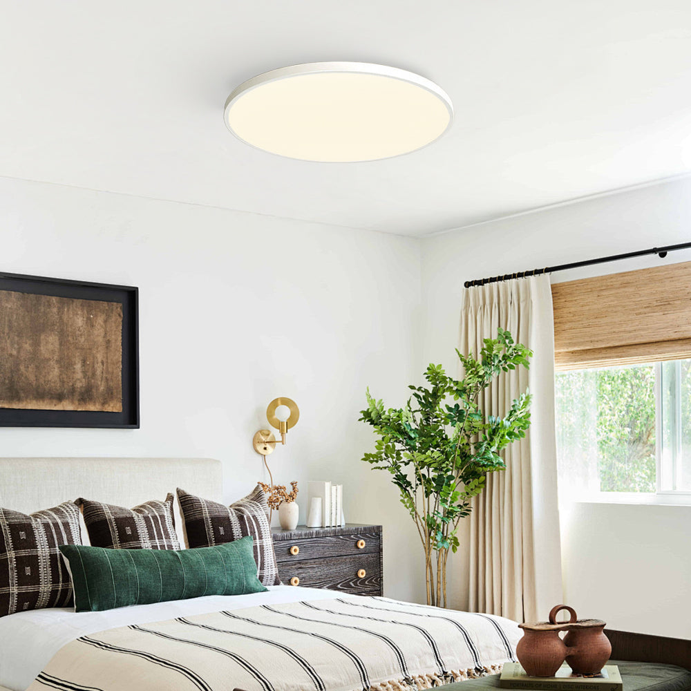 Minimalist white round tywa ceiling light providing soft illumination in a bedroom decorated with greenery