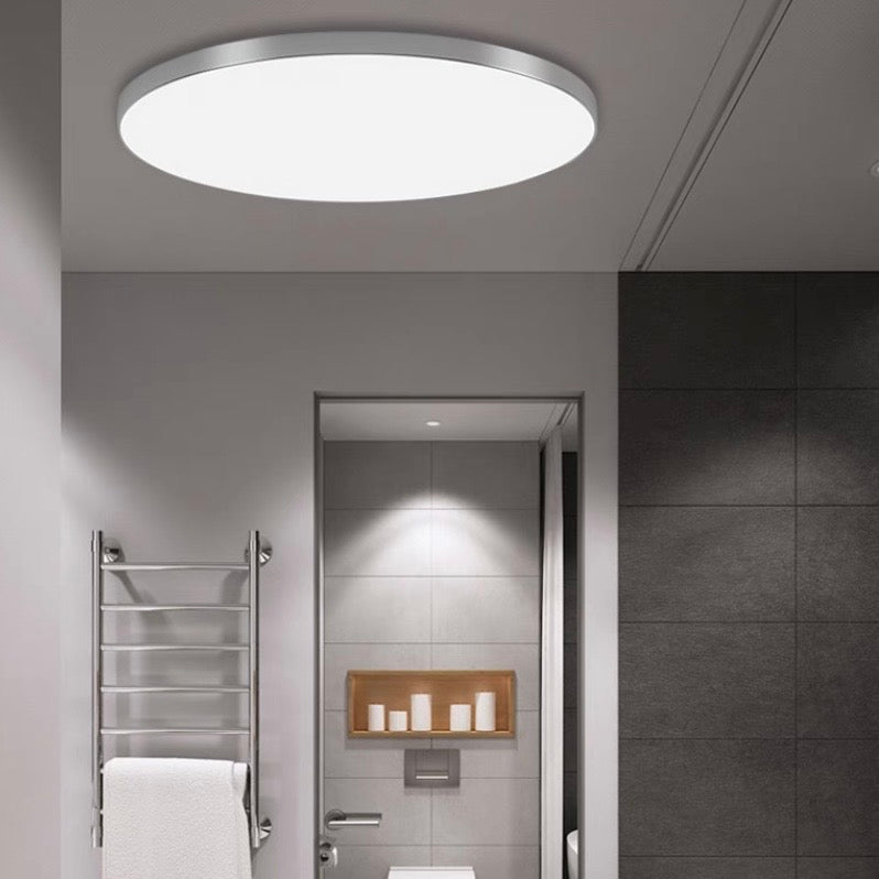 Silver flat panel LED flush mount tywa light installed in a minimalist grey corridor