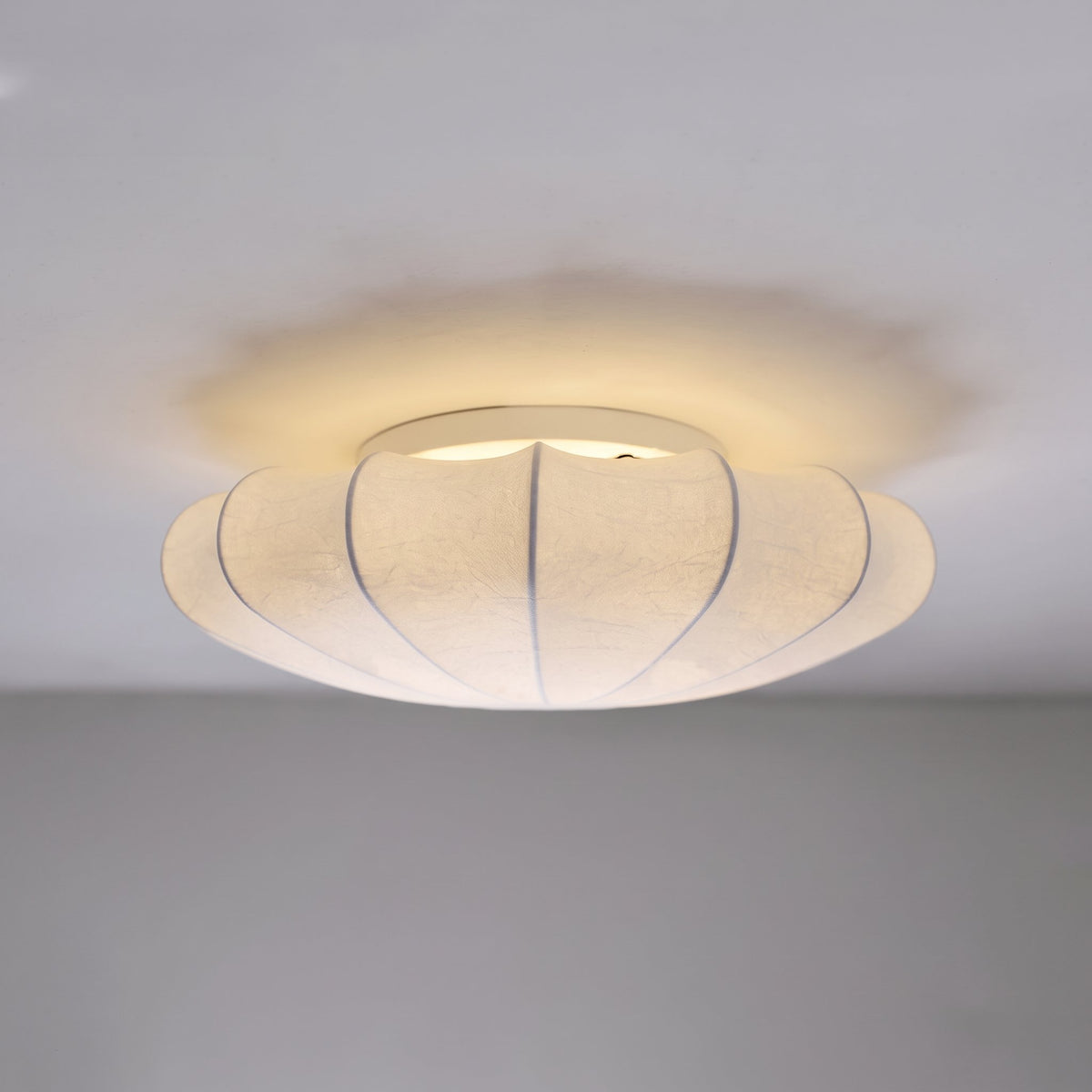 Side view of the Varly silk flush mount ceiling light switched on with a soft glow