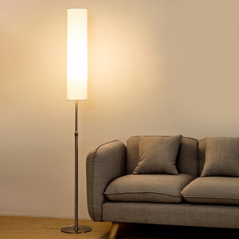 Minimalist standing vatel light with a white fabric shade next to a modern grey sofa