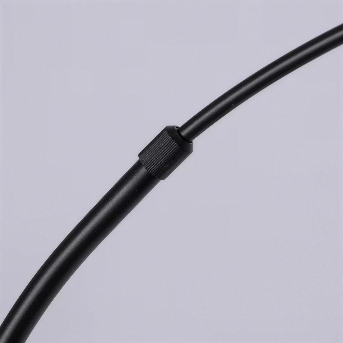 Close-up of the adjustable joint on the curved arm of a black arc floor lamp
